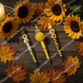 Three handmade sunflower beaded pens with bee charms on dark rustic wooden surface surrounded by deep autumn leaves in moody fall lighting