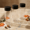 Mom Approved 10 oz Clear Reusable Cup with black lid on warm beige marble surface with autumn leaves