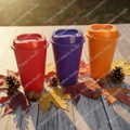 Three colorful plastic tumblers in red, purple, and orange surrounded by natural fall leaves and autumn elements